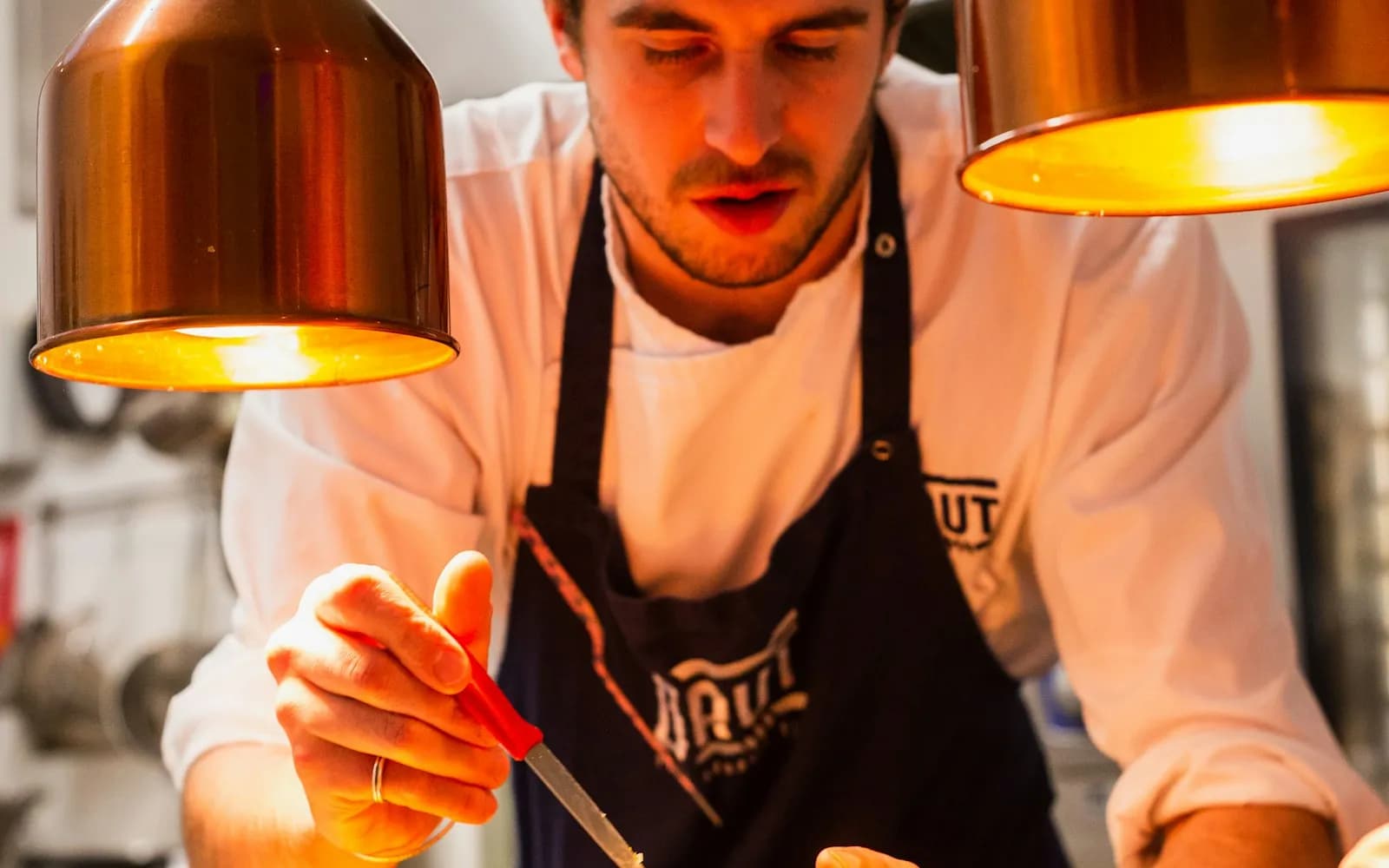 a chef in a rented kitchen coat plating food, representing chef coat & kitchen uniform rental service across the GTA
